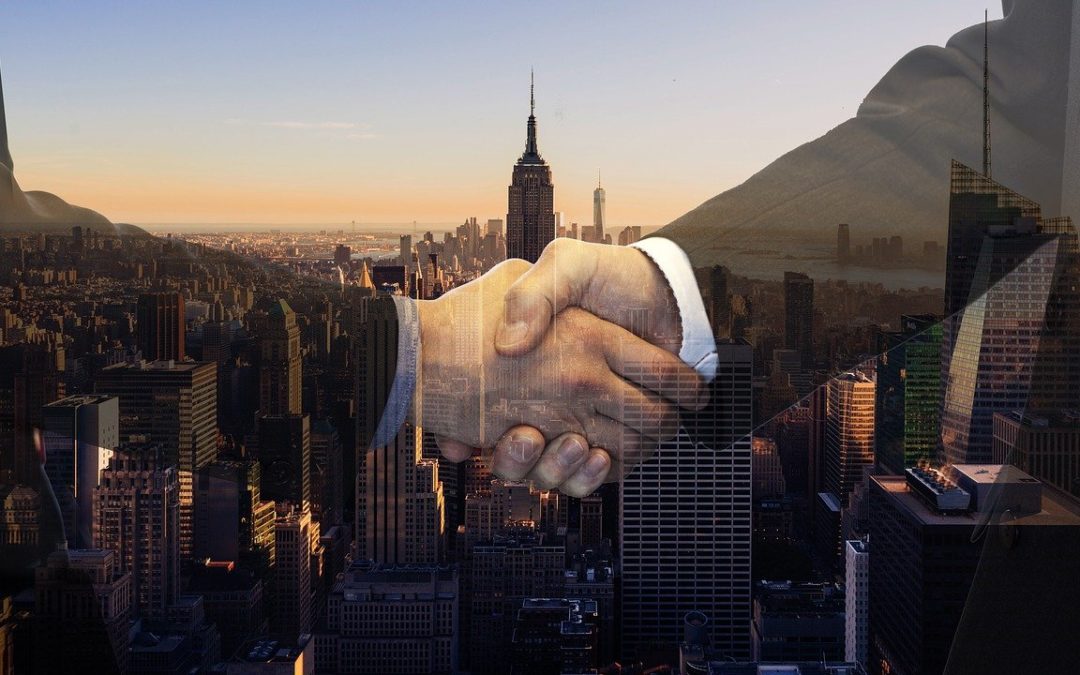 Two people shaking hands in the foreground with a city in the background.