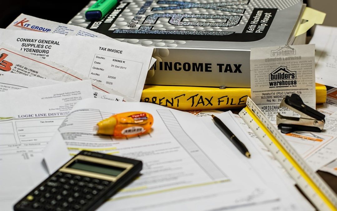 Documents, calculator and books about taxes on a table.