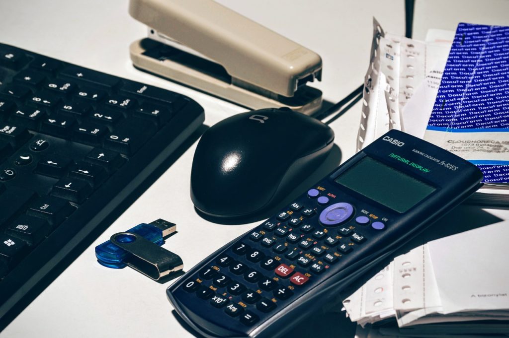 calculator, keyboard, mouse and documents on a table