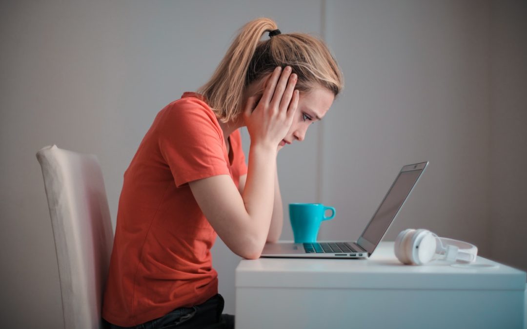 distraught woman looking at her laptop